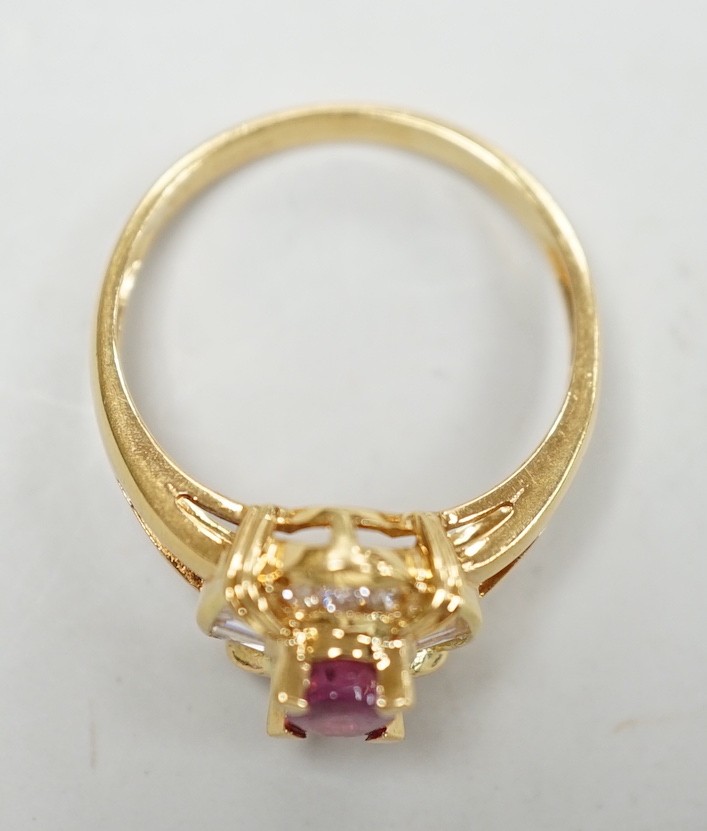 A modern 18ct gold, single stone ruby and trapeze and round cut diamond cluster set dress ring, size O, gross weight 4.7 grams.